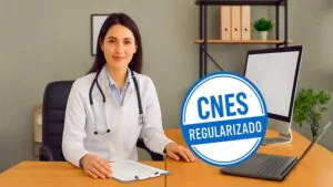 Médica atendendo em consultório com notebook exibindo tela de CNES regularizado